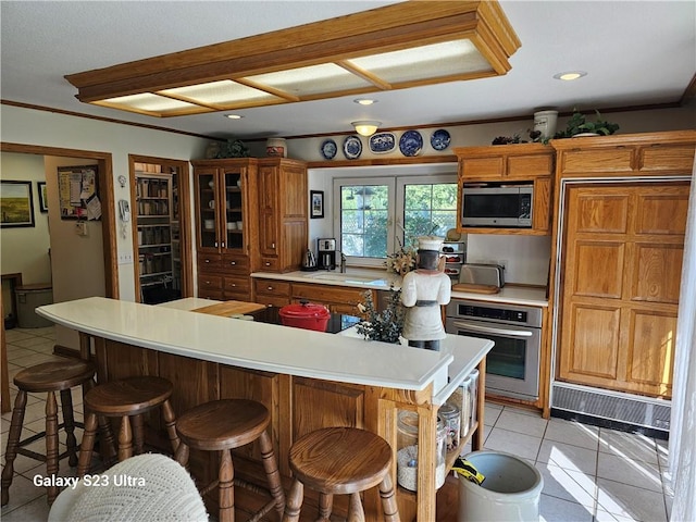 kitchen featuring appliances with stainless steel finishes, a kitchen bar, a kitchen island, and light tile patterned floors