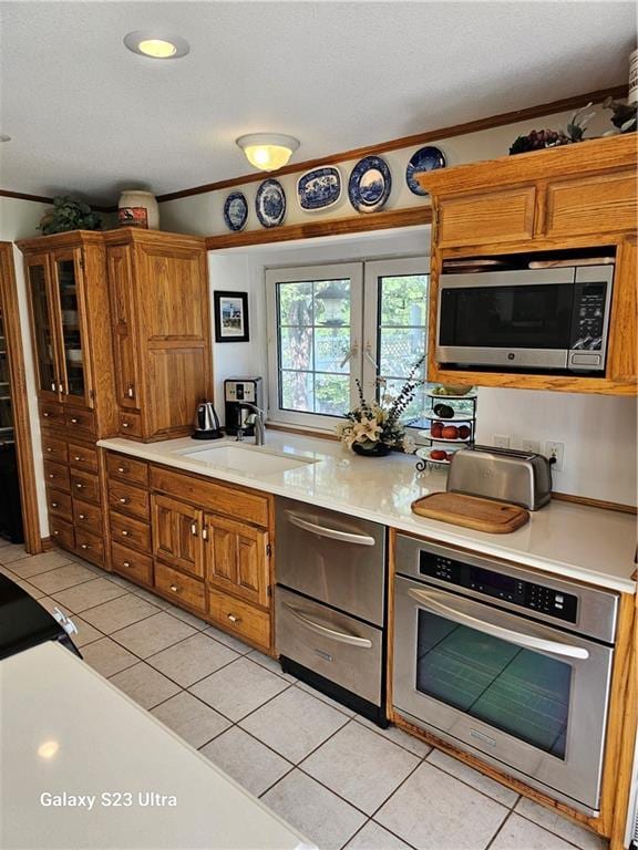 kitchen featuring ornamental molding, appliances with stainless steel finishes, sink, and light tile patterned floors