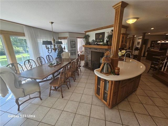 tiled dining room featuring a fireplace, a textured ceiling, and ornate columns