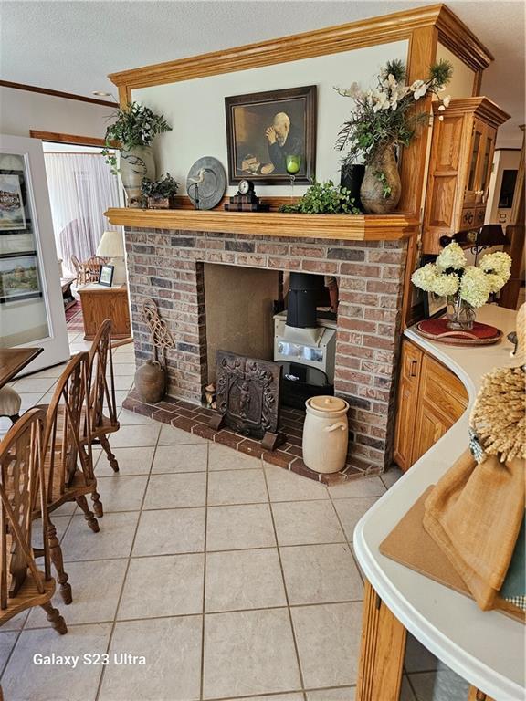 interior space featuring ornamental molding, a fireplace, a textured ceiling, and light tile patterned floors