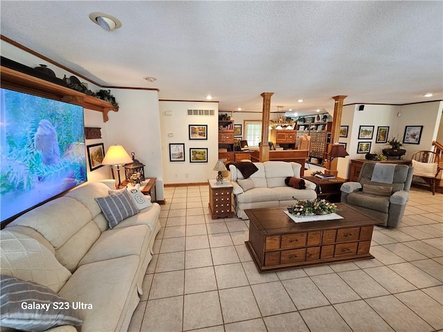 living room with decorative columns, light tile patterned flooring, ornamental molding, and a textured ceiling