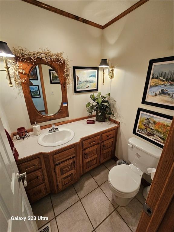 bathroom featuring vanity, tile patterned floors, ornamental molding, and toilet