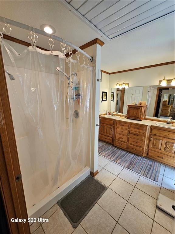 bathroom with tile patterned flooring, vanity, a shower with curtain, and crown molding