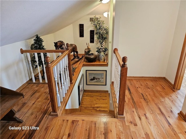 stairs featuring lofted ceiling and wood-type flooring