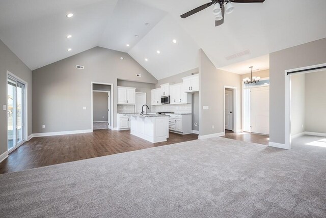 unfurnished living room with high vaulted ceiling, carpet, and ceiling fan with notable chandelier