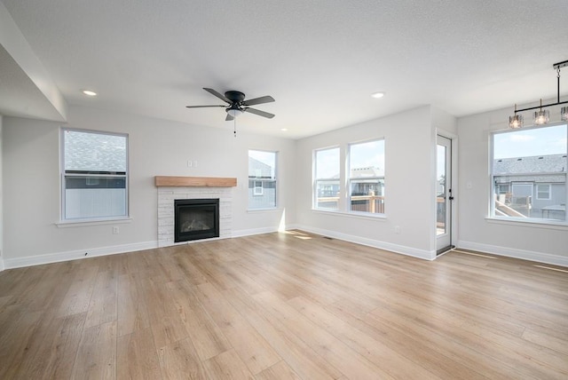 unfurnished living room featuring ceiling fan with notable chandelier and light wood-type flooring