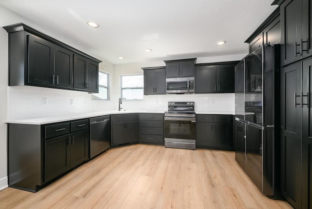 kitchen featuring appliances with stainless steel finishes, light hardwood / wood-style flooring, sink, and backsplash