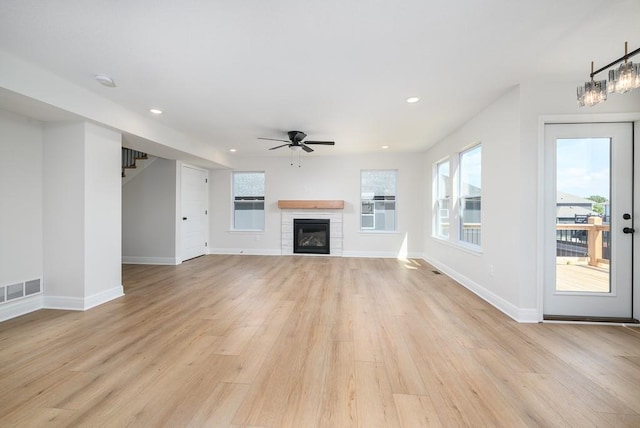 unfurnished living room featuring a fireplace, light wood-type flooring, and ceiling fan