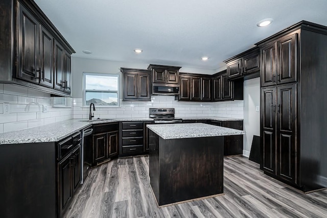 kitchen with a sink, light stone counters, light wood-type flooring, and stainless steel appliances