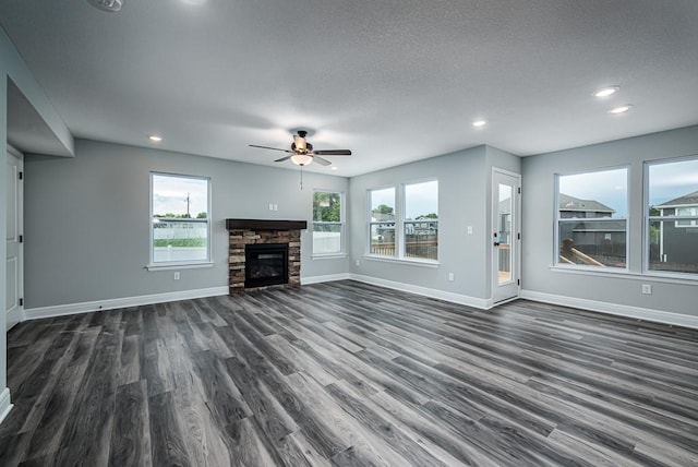 unfurnished living room featuring dark wood finished floors, a fireplace, baseboards, and ceiling fan