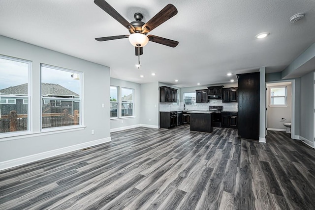 living area with baseboards, a healthy amount of sunlight, ceiling fan, and dark wood finished floors