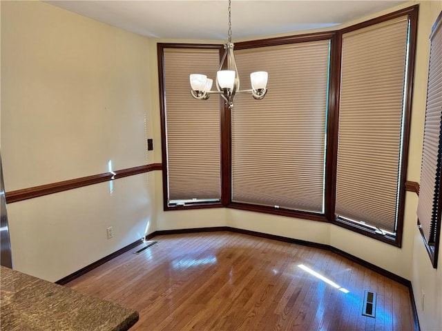 unfurnished dining area featuring a notable chandelier and light hardwood / wood-style flooring