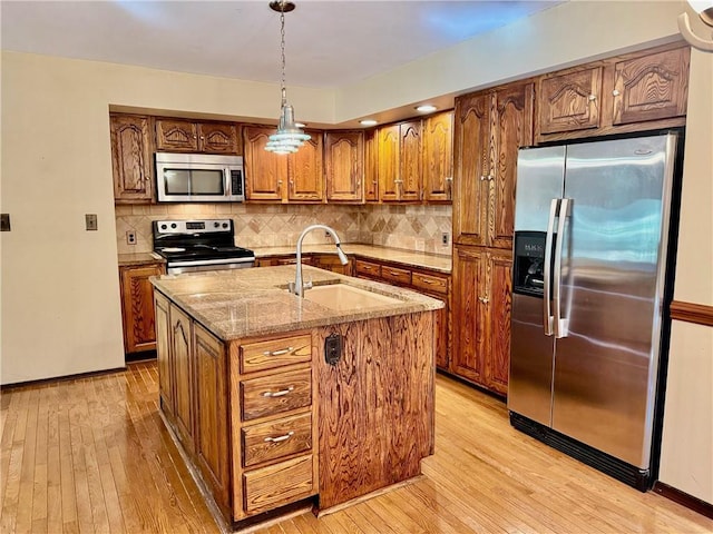 kitchen with pendant lighting, sink, an island with sink, light hardwood / wood-style floors, and stainless steel appliances