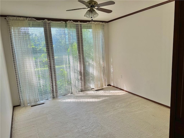 carpeted empty room with plenty of natural light, ceiling fan, and crown molding