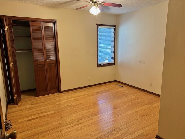 unfurnished bedroom with ceiling fan, a closet, a textured ceiling, and light hardwood / wood-style flooring