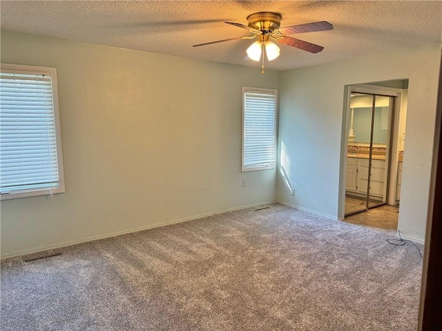 carpeted empty room featuring a textured ceiling and ceiling fan