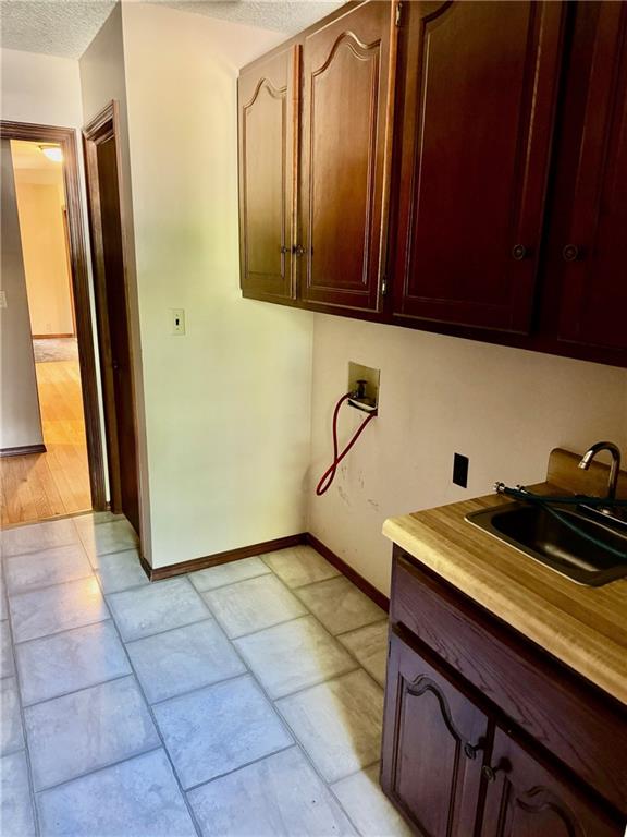 washroom featuring cabinets, hookup for a washing machine, a textured ceiling, and sink