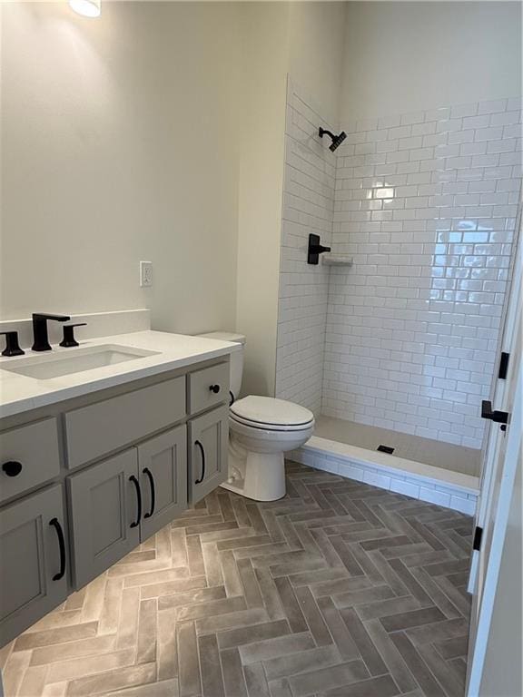 bathroom with a tile shower, vanity, and toilet