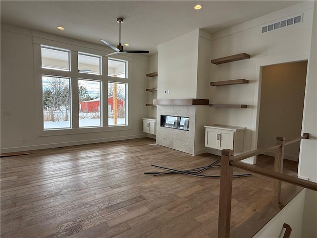 unfurnished living room with a tile fireplace, ceiling fan, and light hardwood / wood-style floors