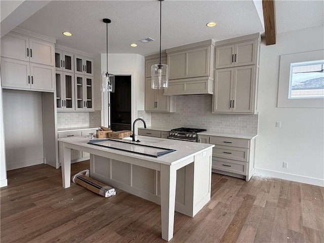 kitchen featuring hanging light fixtures, high end stainless steel range oven, beamed ceiling, a kitchen bar, and a center island with sink