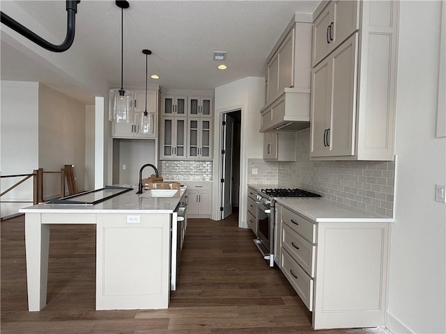 kitchen featuring stainless steel range, a kitchen island with sink, sink, hanging light fixtures, and range hood