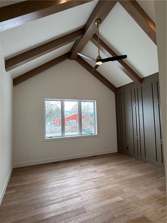 additional living space featuring vaulted ceiling with beams and light hardwood / wood-style floors