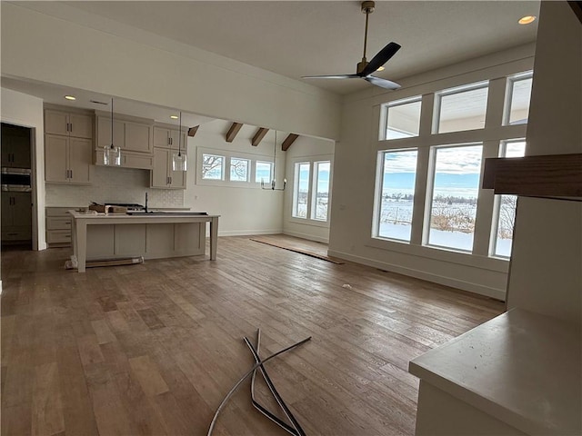 unfurnished living room with ceiling fan, sink, lofted ceiling with beams, and wood-type flooring