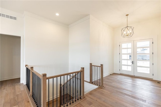 interior space with a chandelier, light wood-type flooring, and french doors