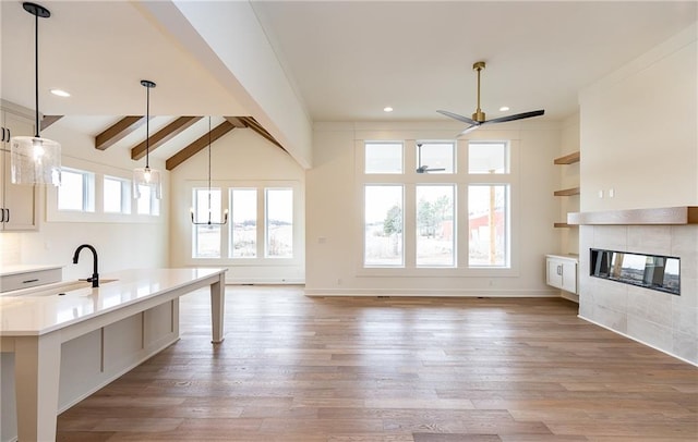 kitchen featuring pendant lighting, sink, light hardwood / wood-style flooring, and a tile fireplace