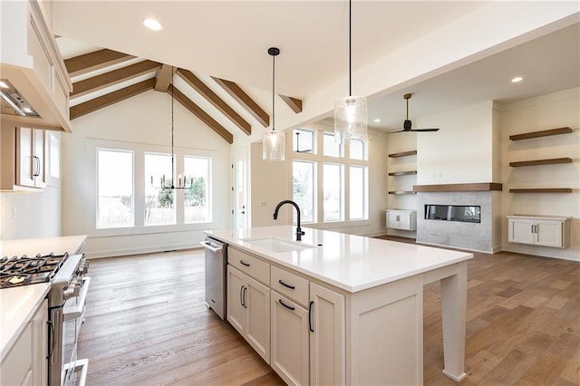 kitchen with pendant lighting, sink, white cabinets, custom exhaust hood, and a kitchen island with sink