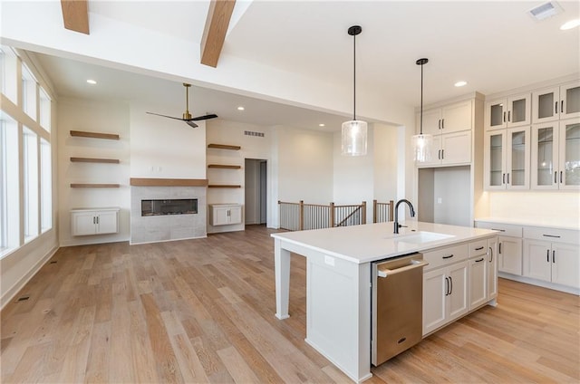 kitchen featuring white cabinetry, dishwasher, sink, hanging light fixtures, and a center island with sink