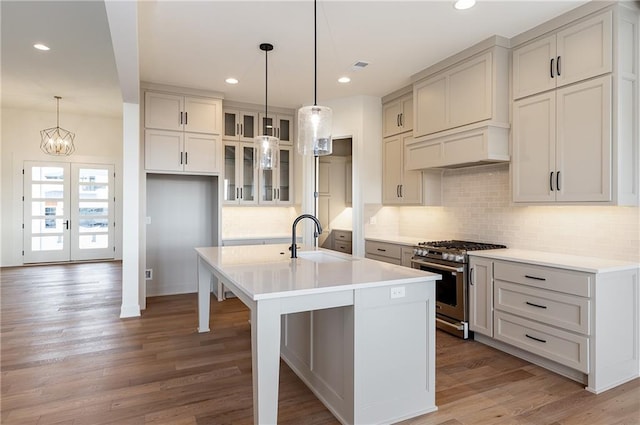 kitchen with hardwood / wood-style floors, sink, hanging light fixtures, a kitchen island with sink, and stainless steel range with gas stovetop