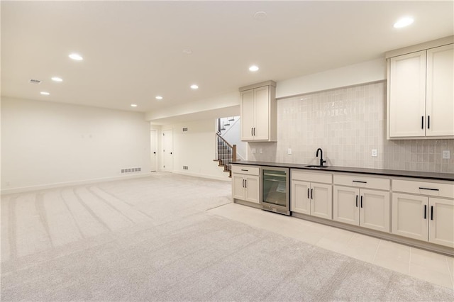 kitchen with sink, light carpet, beverage cooler, and decorative backsplash