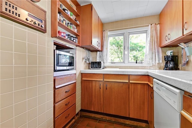 kitchen featuring tasteful backsplash, white dishwasher, tile walls, and dark tile patterned floors