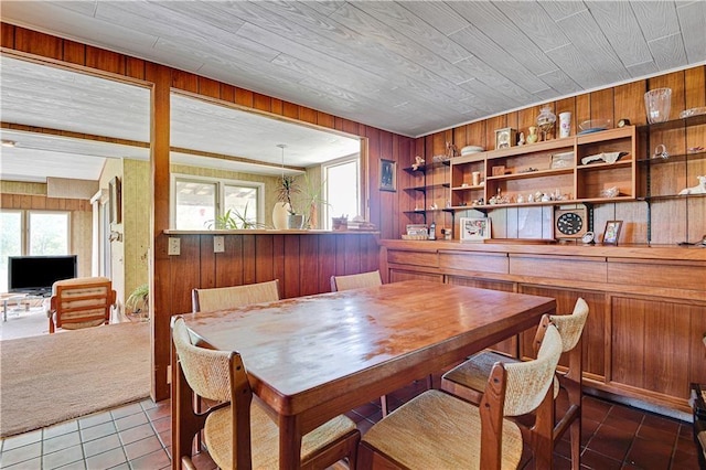 dining room with dark tile patterned floors and wooden walls