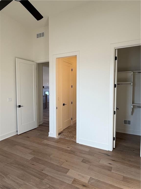 unfurnished bedroom featuring a towering ceiling, light wood-style flooring, and visible vents