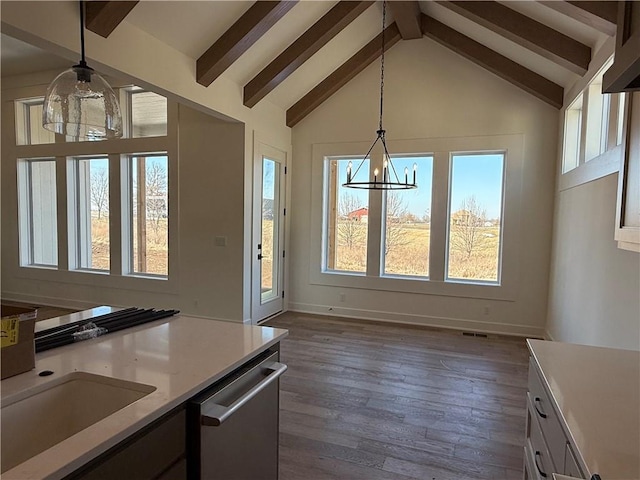 kitchen with beam ceiling, light countertops, a chandelier, pendant lighting, and stainless steel dishwasher