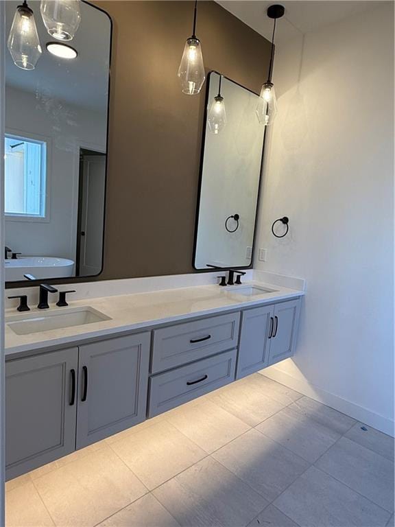 bathroom with double vanity, baseboards, a sink, and tile patterned floors