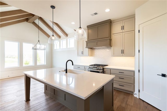 kitchen featuring high end stainless steel range, a sink, light countertops, tasteful backsplash, and visible vents