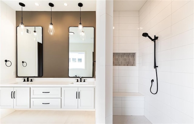 full bathroom featuring double vanity, recessed lighting, a tile shower, and a sink