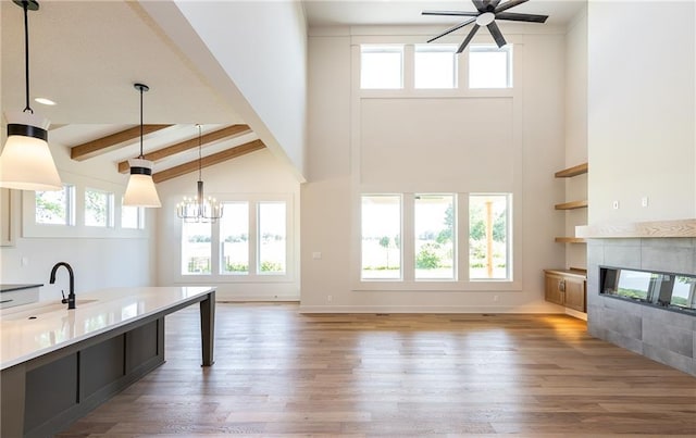 unfurnished living room with dark wood finished floors, a healthy amount of sunlight, a sink, and beamed ceiling