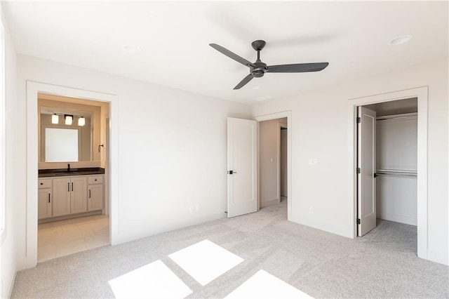 unfurnished bedroom with connected bathroom, light colored carpet, a sink, a spacious closet, and a closet