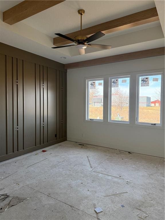 empty room with a tray ceiling, beam ceiling, and ceiling fan