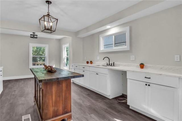 kitchen featuring dark stone countertops, a kitchen island, sink, dark hardwood / wood-style floors, and white cabinets