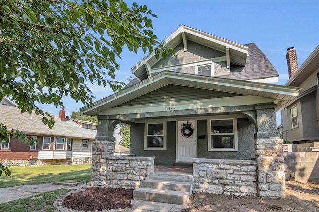 view of front of house with a porch, roof with shingles, and stucco siding