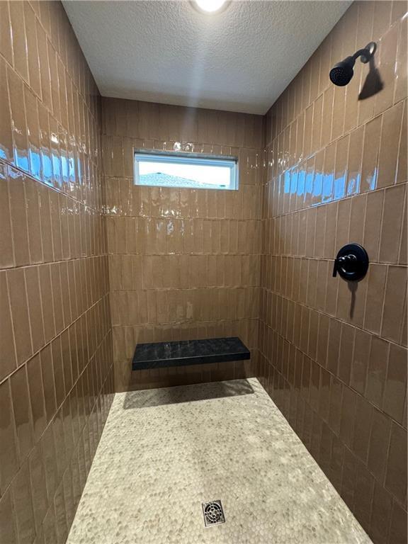 16700 NW 124th St, Platte City, MO 64079 - bathroom featuring a tile shower and a textured ceiling