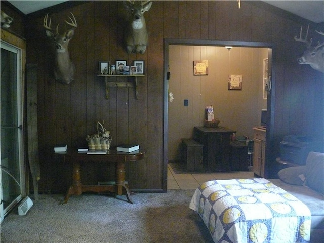 carpeted bedroom featuring wooden walls and lofted ceiling