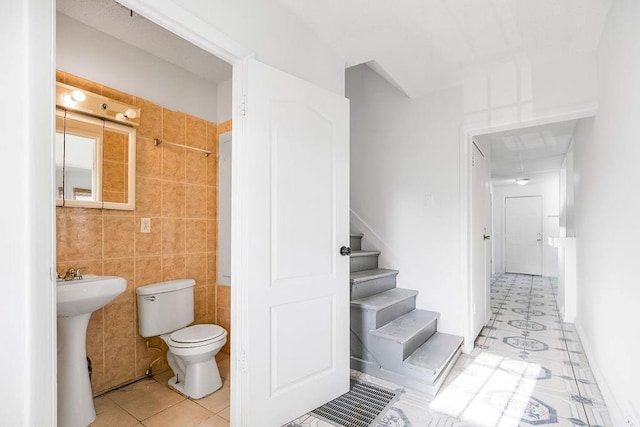 bathroom featuring tile walls, tile patterned floors, and toilet