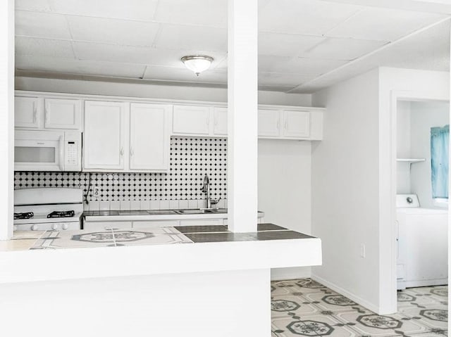 kitchen featuring light tile patterned flooring, white cabinetry, white appliances, washer / dryer, and sink