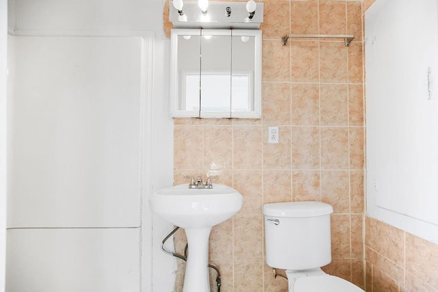 bathroom featuring toilet and tile walls